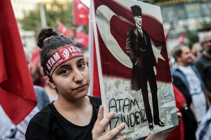 A woman holds a placard picturing Turkisk national flag and Turkey's first president and founder of modern Turkey Mustafa Kemal Ataturk in Istanbul, on August 30, 2016