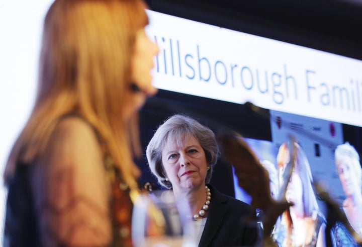 Theresa May watches as Margaret Aspinall receives the award