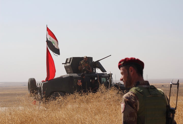 A Kurdish Peshmerga fighter looks out on a convoy of Iraqi forces as they both worked in tandem to detect and dismantle IEDs.