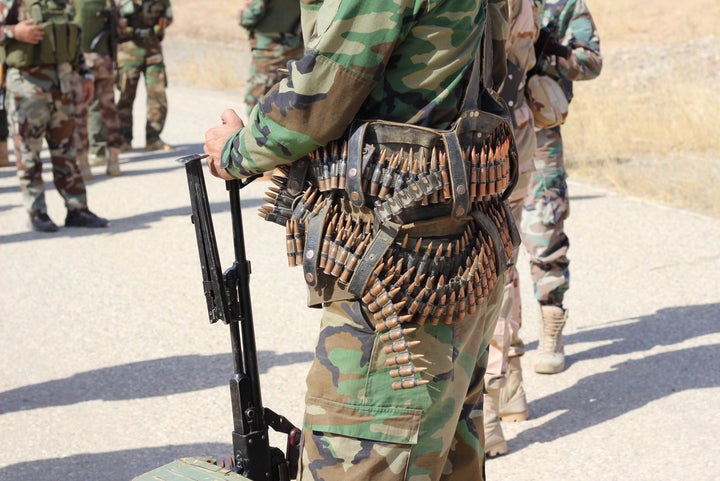 A Kurdish Peshmerga fighter waits for his colleagues to dismantle an IED blocking the road in Hasan al Sham.