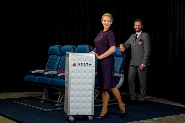 Flight attendant uniforms include a three-button suit with Delta logo-patterned tie and a dress with matching gloves and handbag. 