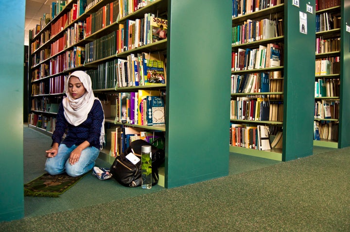 A woman has a quiet moment of prayer in a quiet corner of a library.