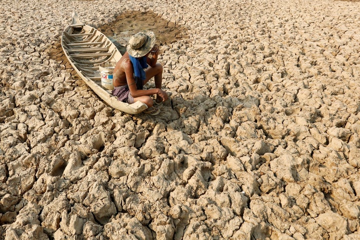 A fisherman sits on his boat in a dried-up pond in drought-stricken Cambodia in May 2016. Climate change has been linked to a