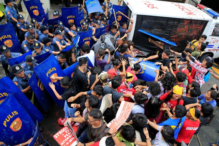 Activists and Indigenous People's groups clash with anti-riot policemen in front of the U.S. Embassy in Manila.
