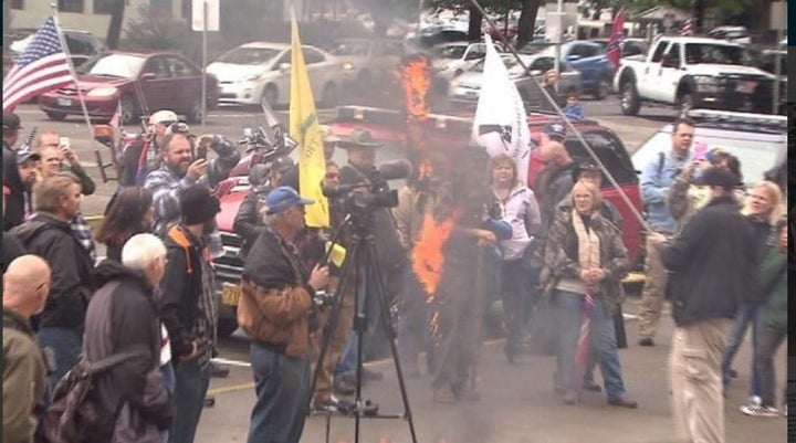 Gun rights advocates hang and burn an effigy of Brown on the steps of the Oregon Capitol in September. The man dangling the effigy is wearing a mask.