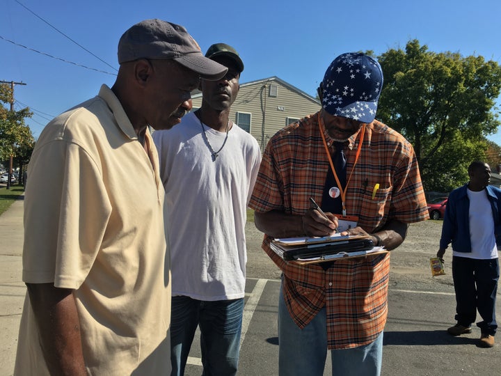 Muhammad As-saddique Abdul-Rahman (right) helps Richard Simms, 57, and Keith Butts, 53, fill out their voter registration forms in the Richmond neighborhood of Blackwell on Oct. 17.