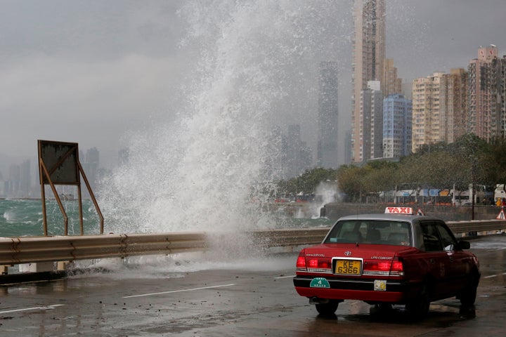 A taxi drives past a big wave on a waterfront as Typhoon Haima approaches in Hong Kong.