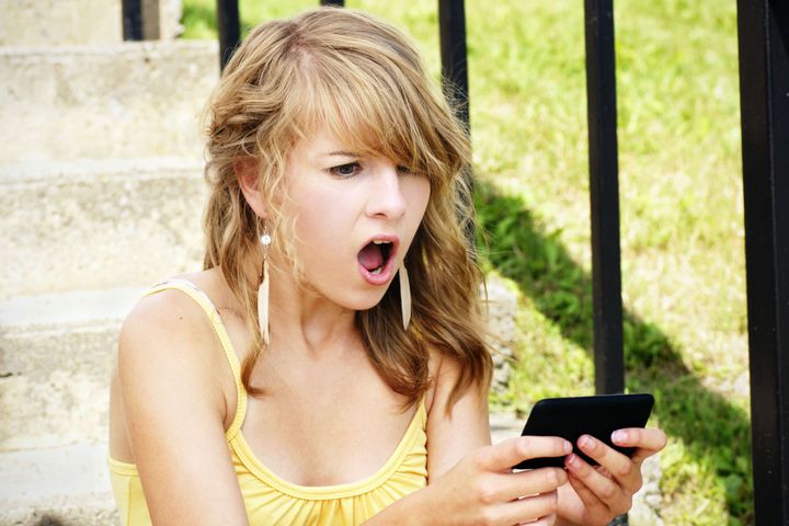 Young woman shocked at what she's reading about someone online.