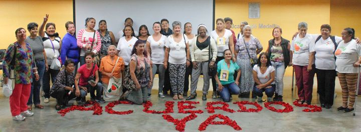 Members of the Women Walking for Truth gather behind the message "Accords Now" scrawled across the stage with rose petals for an October 14, 2016 event commemorating Operation Orion.