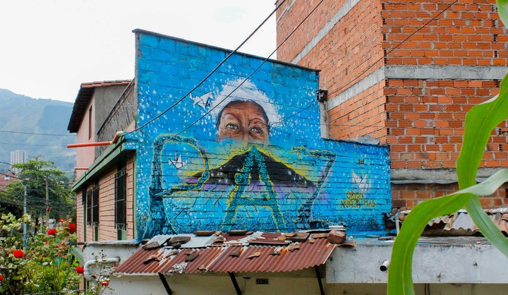 "Orion never again" reads a mural commemorating 14 years since Operation Orion laid seige to the neighborhood of Comuna 13 in Medellín, Colombia's second largest city. The eyes of human rights activist Luz Elena Galeano Laverde look on as peace grows and origami doves flutter.