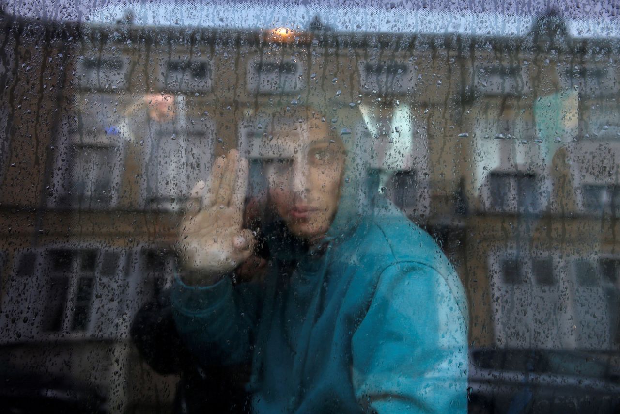 An adolescent Afghan migrant waves from a van as he departs with six others from an emergency shelter in Saint Omer, France, on Oct. 18, 2016, en route to the U.K.