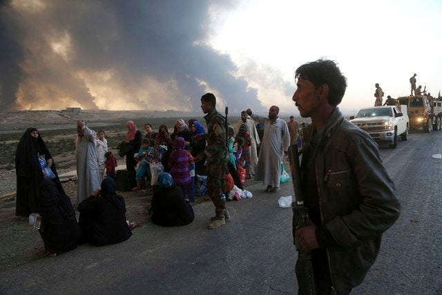 Smoke rises as people flee their homes during clashes between Iraqi security forces and members of the Islamic State group, on Tuesday, Oct. 18, 2016.