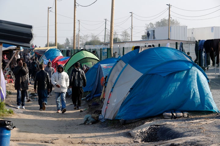 Migrants walk in an alley near tents and makeshift shelters on the eve of the evacuation and dismantlement of the camp called the