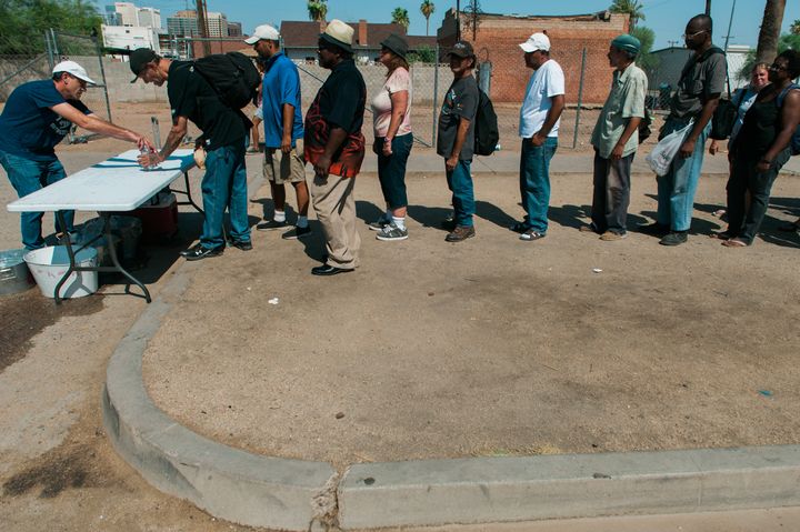 People struggling with homelessness waiting in line for food and beverages in Phoenix, Arizona.