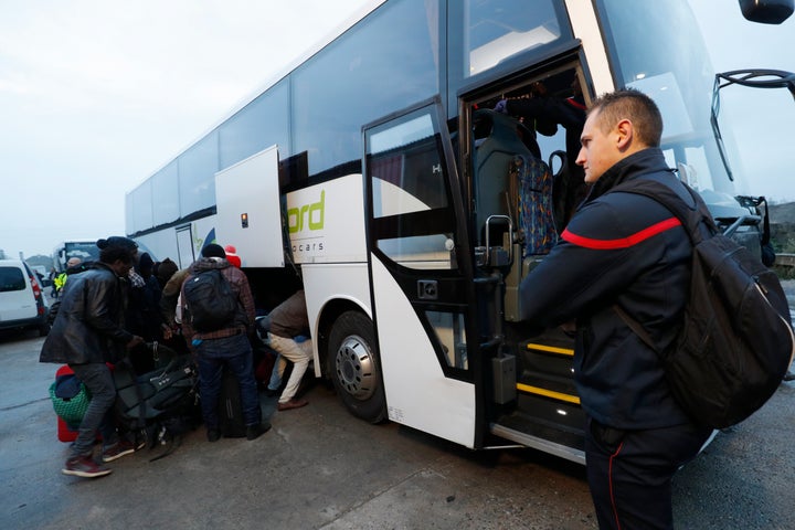 Migrants place their belongings on a bus at the start of their evacuation and transfer in Calais on Monday