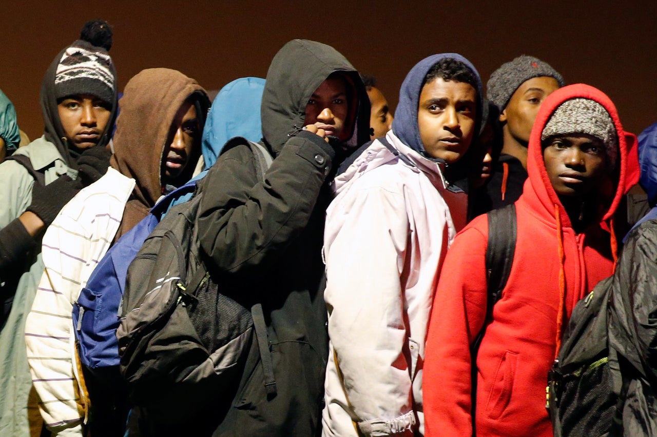 Migrants and refugees in the "Jungle" with their belongings form a line as they prepare to evacuate and be transferred to reception centers across France, October 24, 2016.