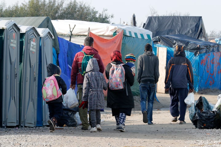 A migrant family walks with their belongings on Sunday, the day before the evacuation of 'The Jungle' at Calais