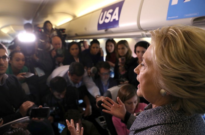 Reporters ask Hillary Clinton questions aboard her campaign plane.