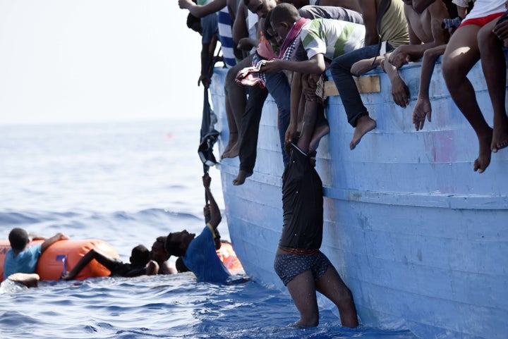 A migrant hangs from a boat as they wait to be rescued as they drift in the Mediterranean Sea, some 12 nautical miles north of Libya, on October 4, 2016.