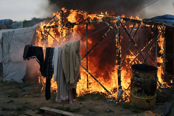 Washing still hangs on a line as a structure burns in the background