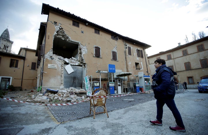 A police officer stands next to a collapsed building after an earthquake in Visso, central Italy.