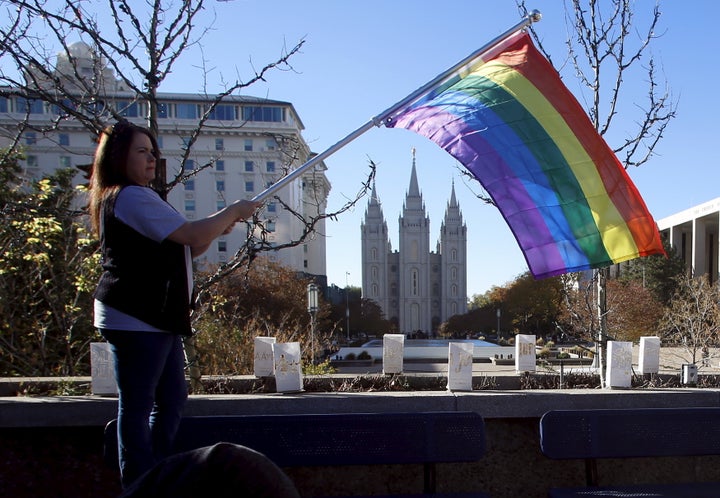 Sandy Newcomb stands with a flag near the Salt Lake Temple after members of The Church of Jesus Christ of Latter-day Saints mailed their membership resignation to the church in Salt Lake City, Utah November 14, 2015. The resignations were prompted by the Mormon church policy barring the children of married same-sex couples from receiving baptism.