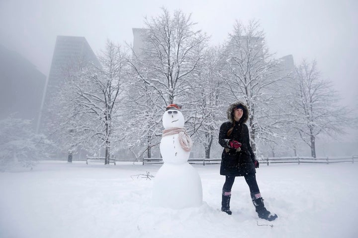 <p>MacKenzie Perkins walks past a snowman she built in a park during blizzard conditions in Chicago, in 2015.</p>