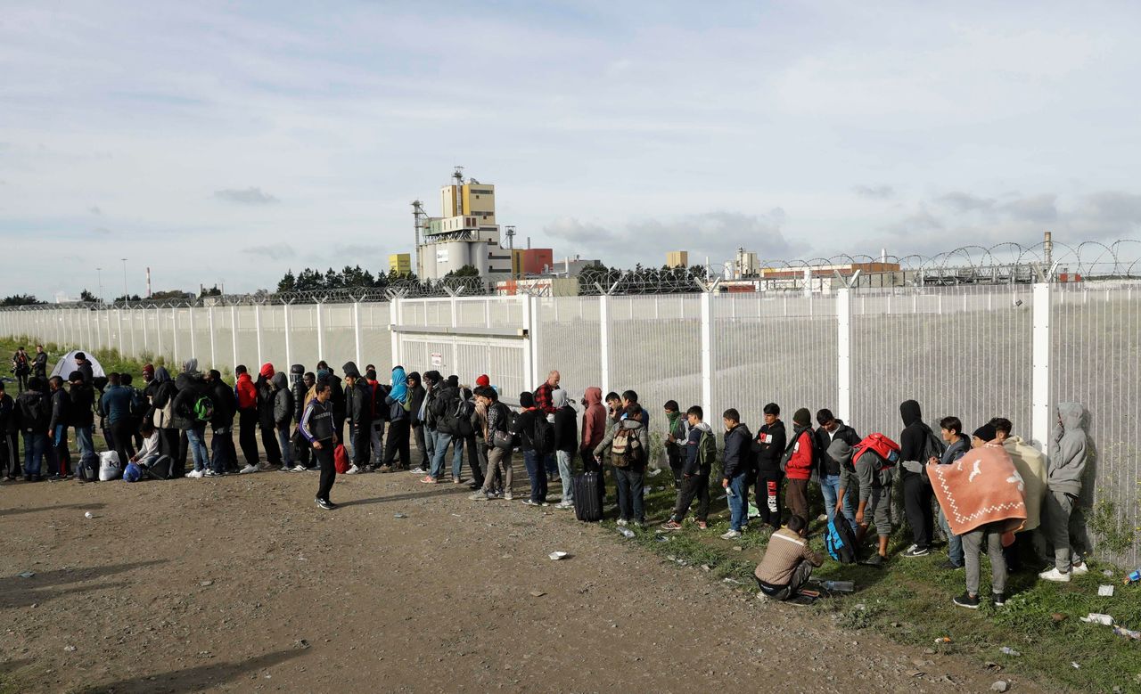 Migrants queue for busses.