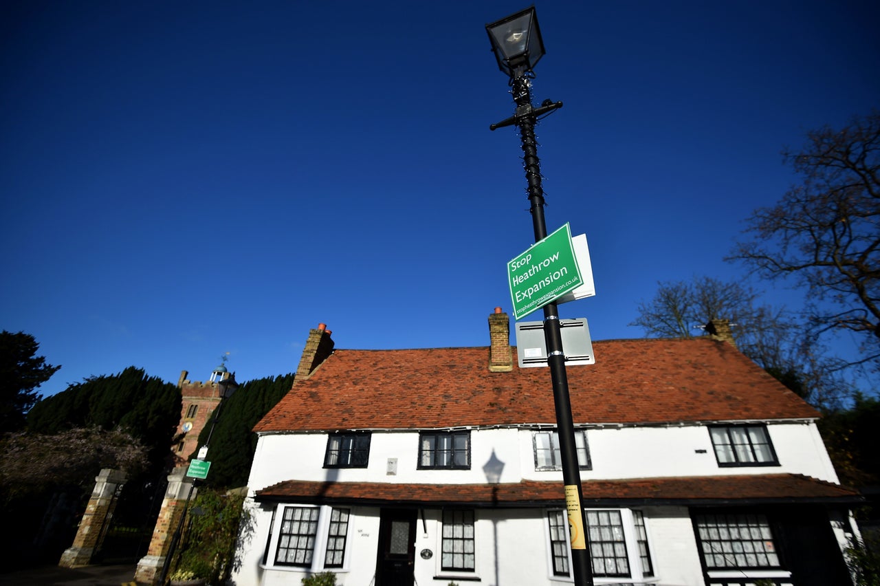 Campaign materials adorn a streetlight close to historic buildings in Harmondsworth