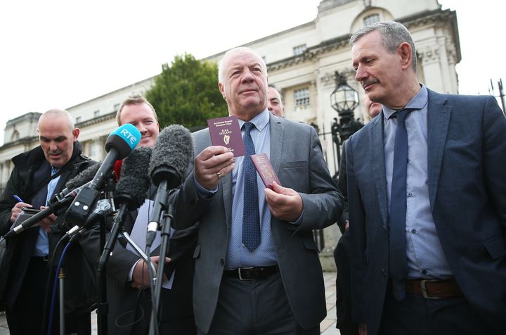 Raymond McCord holds up his newly issued Irish passport alongside his British passport outside the High Court in Belfast.
