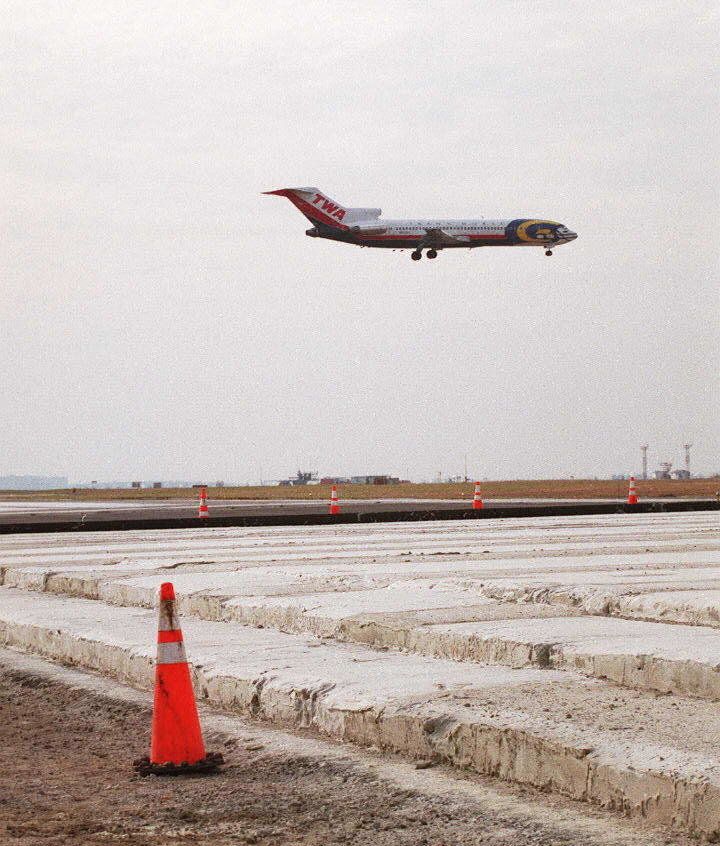 A TWA aircraft flies over the Foam Arrestor bed at the end of runway 4R-22L at John F. Kennedy International airport in New York. Designed to stop a large aircraft traveling at 75 knots, the bed is comprised of about 2,000 aerated cellular cement blocks. 