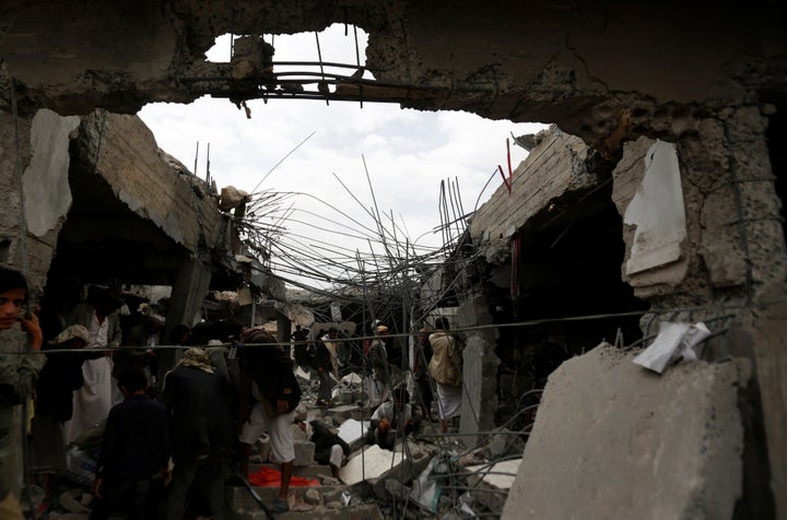 People gather in a building destroyed by Saudi-led airstrikes in the northwestern city of Amran, Yemen, on Sept. 8, 2016.