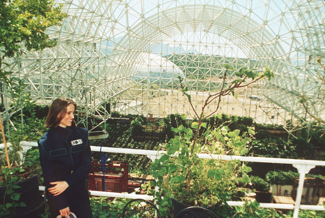 Abigail Alling stands on the balcony of the living quarters inside Biosphere 2 above the agricultural growing area of the complex in Oracle, Arizona. Scientists are still using the facility, only now the focus is figuring out how we'll survive on our own warming planet.