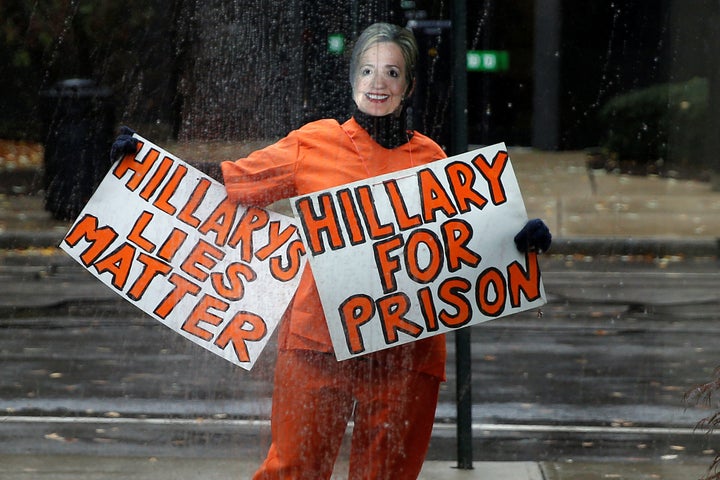 A person wearing an orange jumpsuit and dressed as Hillary Clinton stands outside Donald Trump's campaign event in Manchester