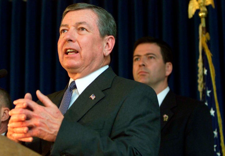 James Comey, then U.S. Attorney for the Southern District of New York, stands behind Attorney General John Ashcroft as he announces a series of indictments on April 9, 2002.