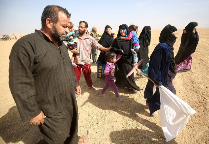 Displaced Iraqis from the Bajwaniyah village, about 30 kms south of Mosul, carry a white flag as they approach security