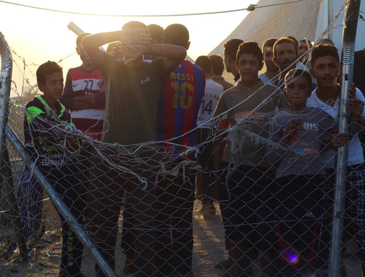 Iraqi men and boys stand inside of a fenced-in area next to a screening center at Debaga camp. Some are detained there for days, others are held for weeks.