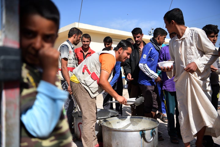 Displaced Iraqi men wait for food at Debaga camp on Oct. 21. Newly arrived men, women and children seek shelter as