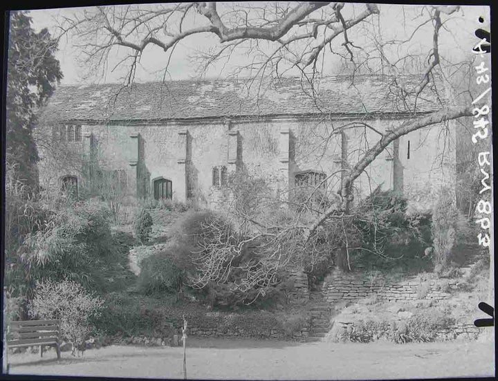 Historic photograph of Bradford-on-Avon Tithe Barn (above) where daisy wheels have been found, thought to have been carved into the stonework to protect crops. The barn today (below)