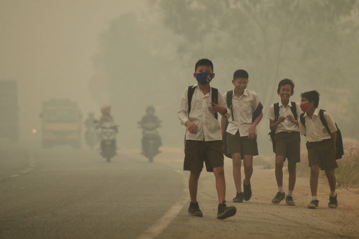 Students walk along a street as they are released from school to return home earlier due to the haze in Jambi, Indonesia's Jambi province.