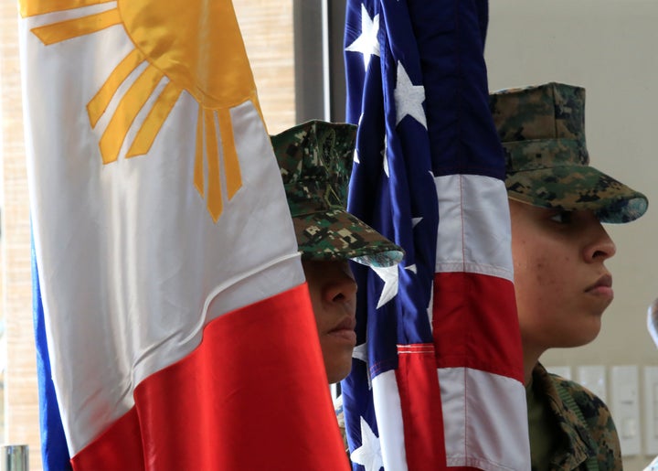 Philippine-U.S. marine corps stand at attention with the Philippine and American flags.