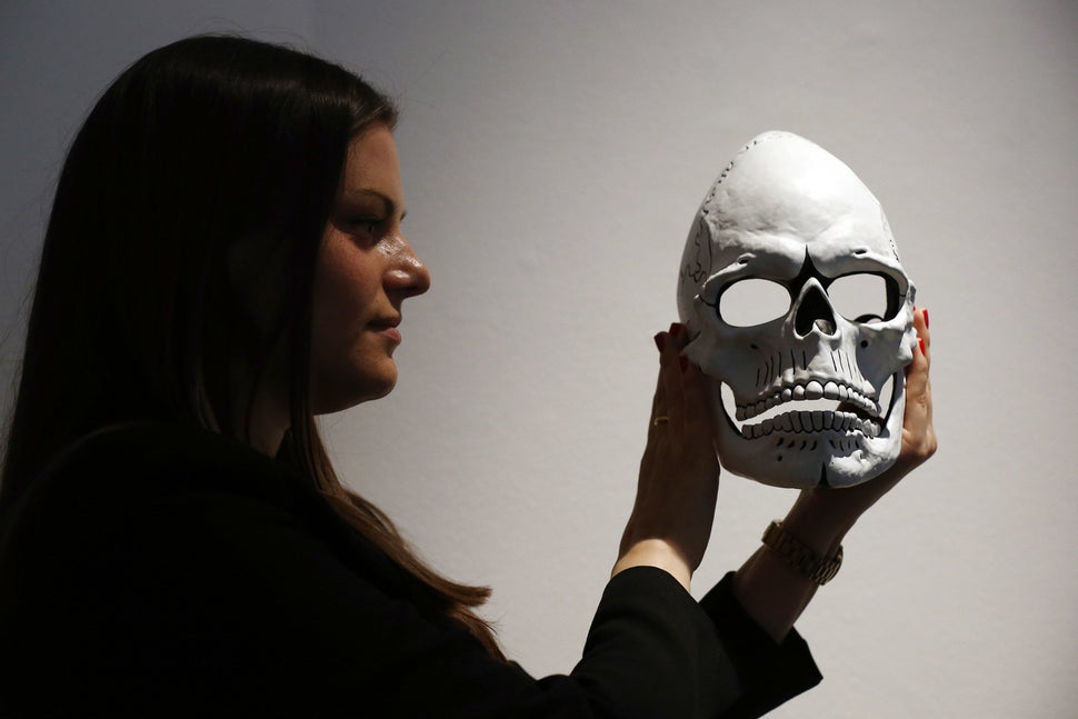 A woman poses with the mask from James Bond's Day of the Dead costume, worn by Daniel Craig in "Spectre," during a photocall