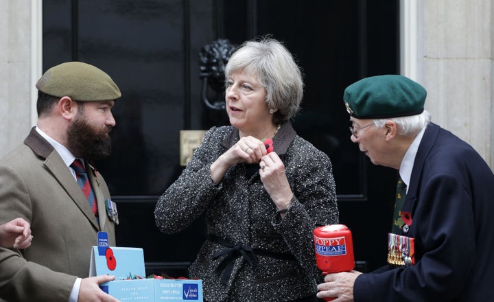 Theresa May, pictured collecting her poppy in Downing Street on Monday, said that 'people should be able to wear their poppies with pride'.