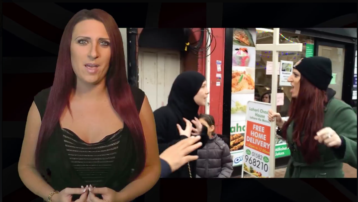 Jayda Fransen speaking in front of footage of herself brandishing a cross