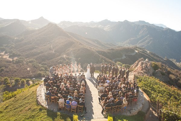 Mountaintop Wedding at Malibu Rocky Oaks in Malibu, California: Picture this: Sweeping vistas of breathtaking mountains, a picturesque gathering of your closest friends and family members, and a wedding album filled with photos as magical as the views you saw that time you took a sunset helicopter ride. Tucked away in sunny California, this unbelievable venue is also home to diverse and sprawling vineyards.