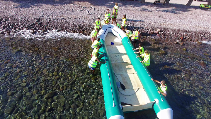 Volunteers belonging to the Light House Relief NGO transport a rubber dinghy, from which a group of arrivals was rescued, to shore. They provide both emergency response for arrivals and recycling services and clean-ups of the local beaches.