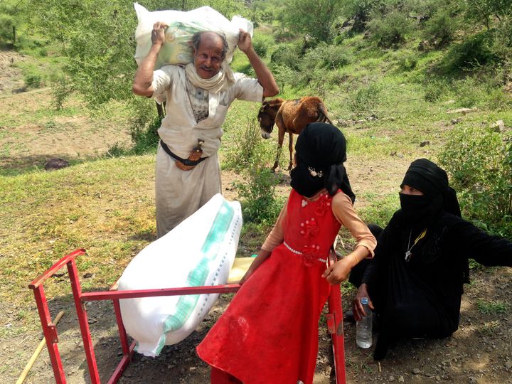 A family in Haymah Dakhliyah carries home their monthly food rations redeemed by voucher with a local market supplier. 