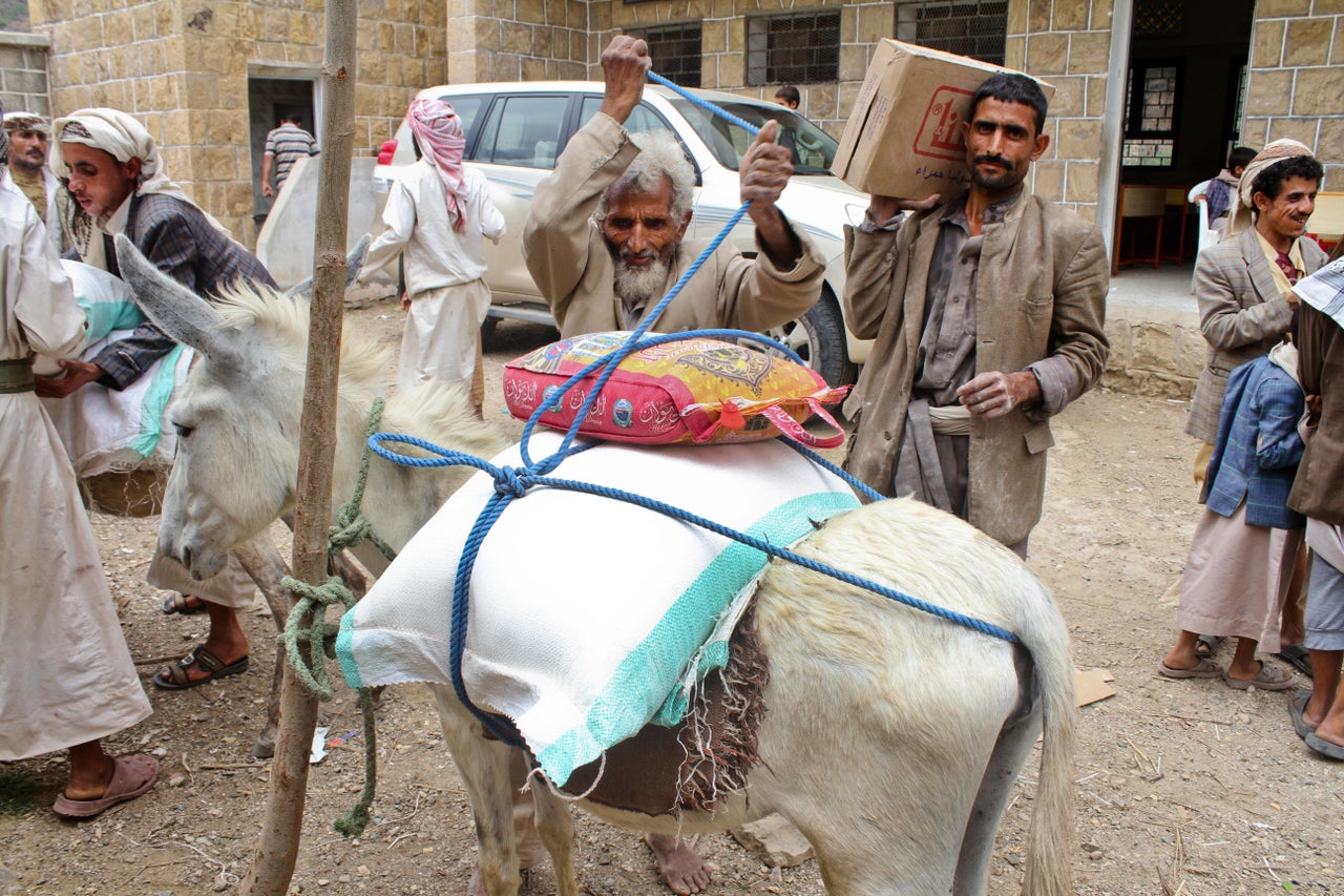 A father carries home his monthly ration of food items provided by Mercy Corps through its voucher system that works with local food suppliers in Haymah Kharijiyah, Sanaa governorate.