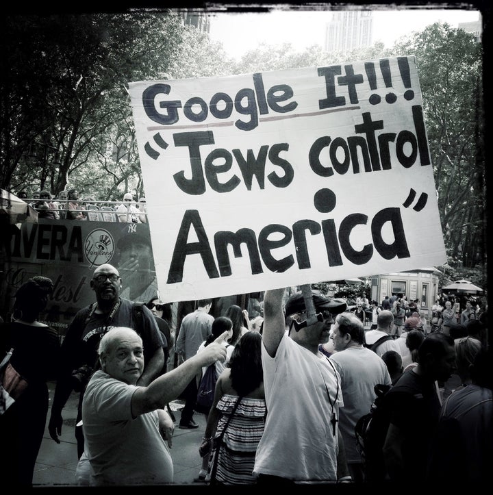  A man holds up an anti-Semitic sign on a crowded Manhattan street.