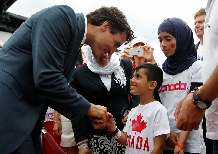 Trudeau grins while greeting a young Syrian refugee.